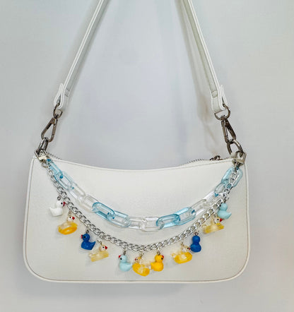 White handbag with colorful charm chain on a light gray background